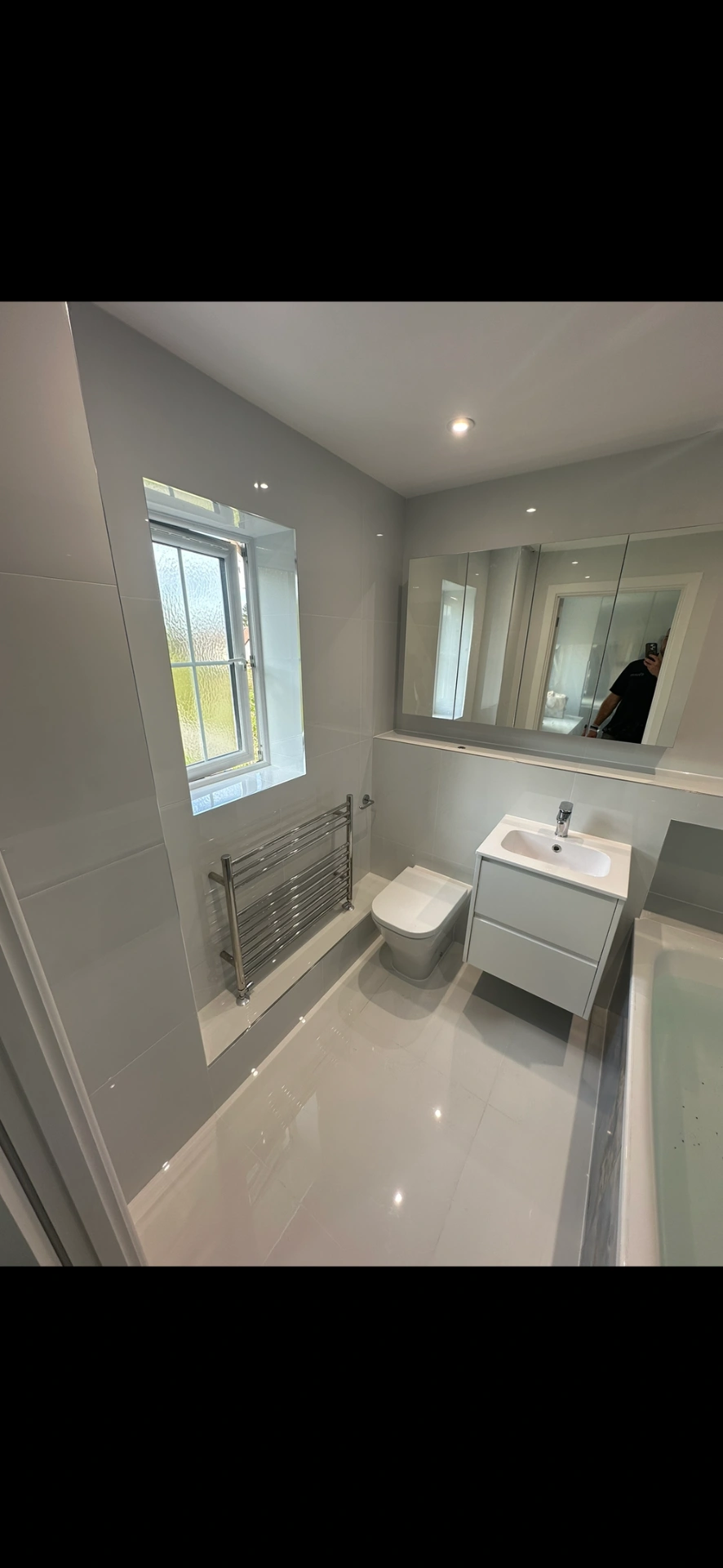 Bright white family bathroom with floating vanity, mirrored cabinet and gloss floor tiles — bathroom installation
