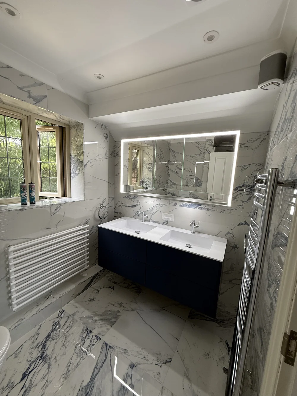 Marble ensuite with double basin navy vanity — fitted bathroom
