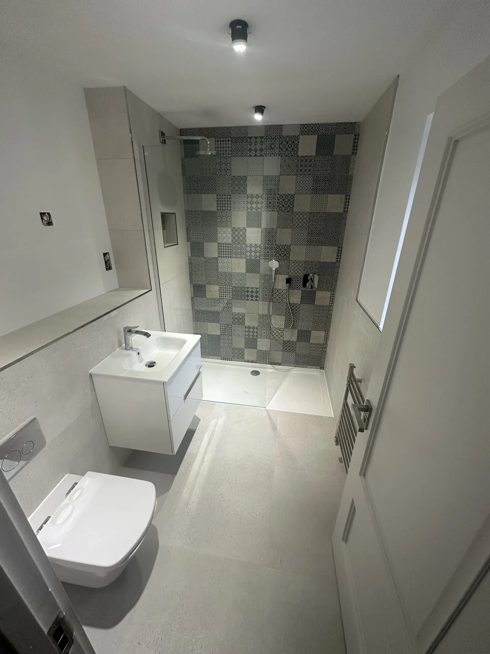 Compact shower room with patchwork feature wall and floating white vanity — bathroom installation